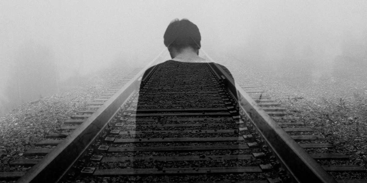 man walking on railway tracks with depression